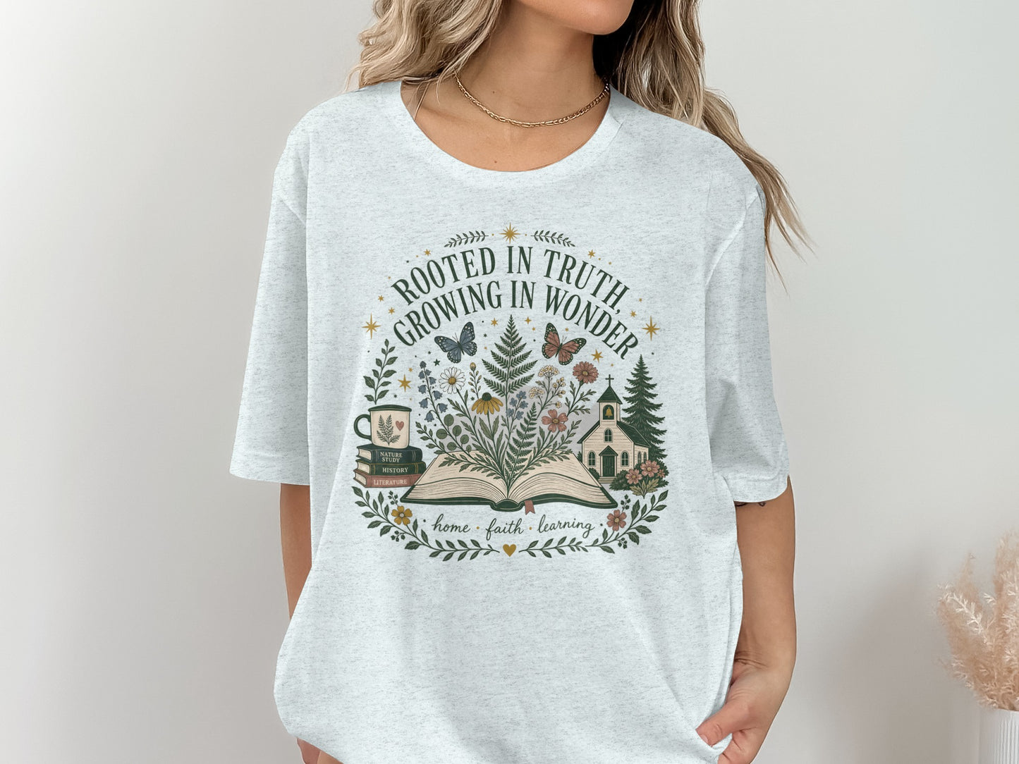 T-shirt with a circular graphic of an open book, flowers, a church, and the text "Rooted in Truth, Growing in Wonder."