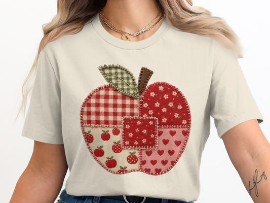 Cream t-shirt with a patchwork apple graphic, featuring red gingham and floral prints.
