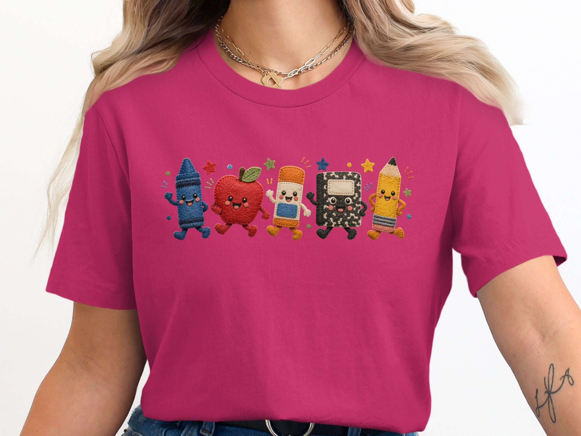 T-shirt with embroidered smiling school supplies: crayon, apple, eraser, notebook, and pencil.