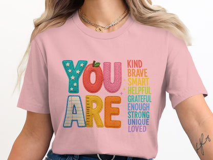 Pink t-shirt with "YOU ARE" text and a list of positive attributes.