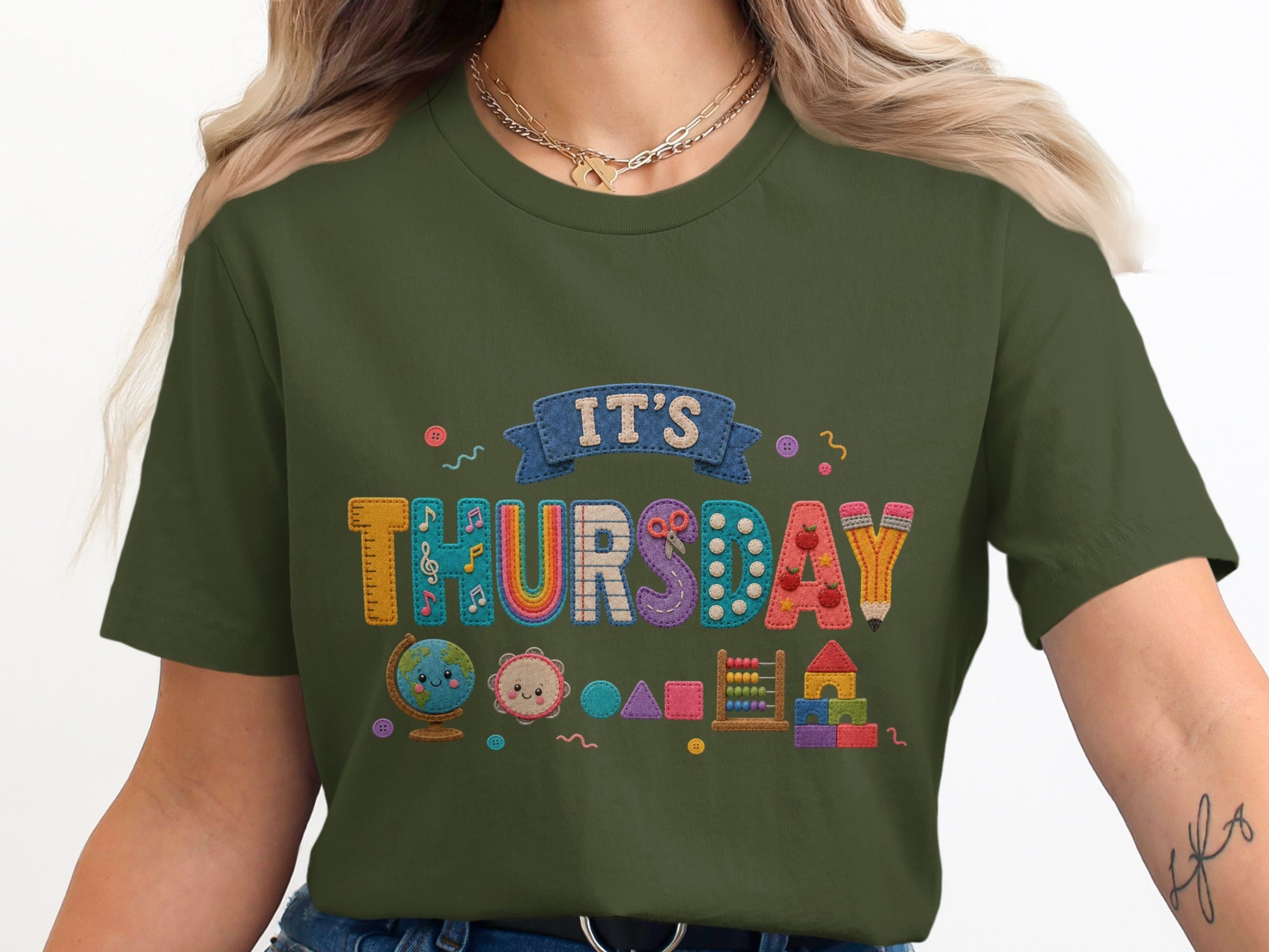 Green t-shirt with colorful embroidered "IT'S THURSDAY" text and school-themed icons.