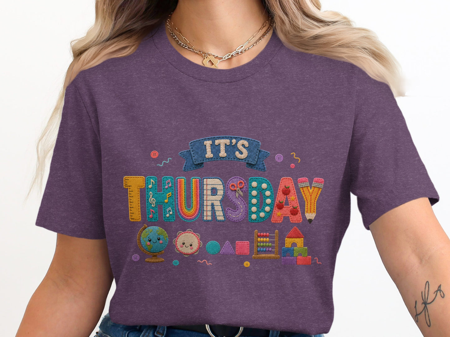 Purple t-shirt with "It's Thursday" design and school-themed applique graphics.