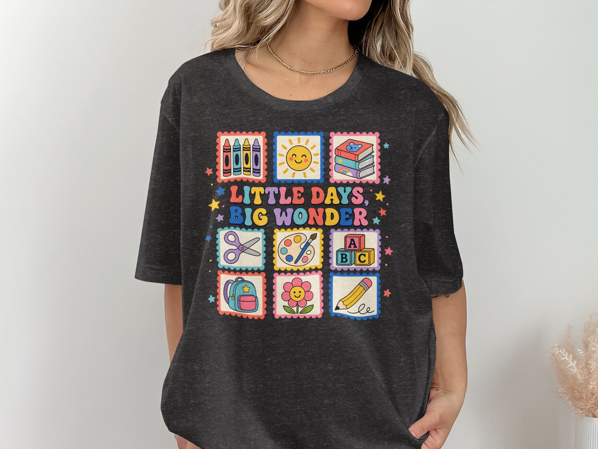 T-shirt with "LITTLE DAYS, BIG WONDER" text and school-themed stamps.