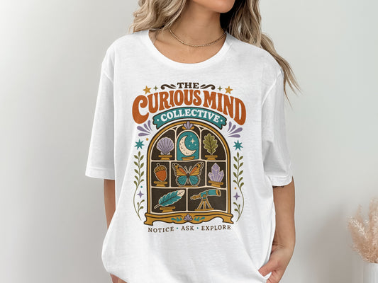 White t-shirt with "The Curious Mind Collective" and nature-themed graphic.