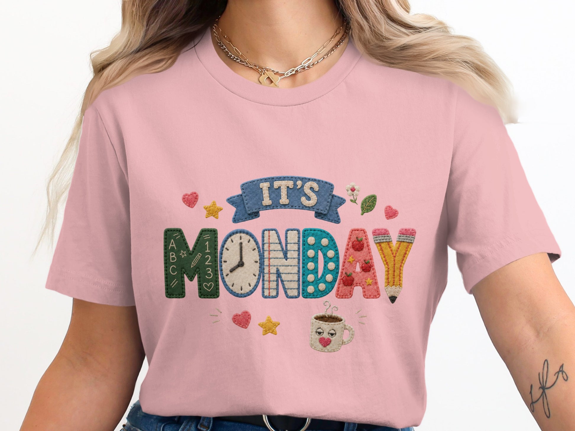 "It's Monday" text with embroidered letters, a clock, and school supplies on a pink t-shirt.