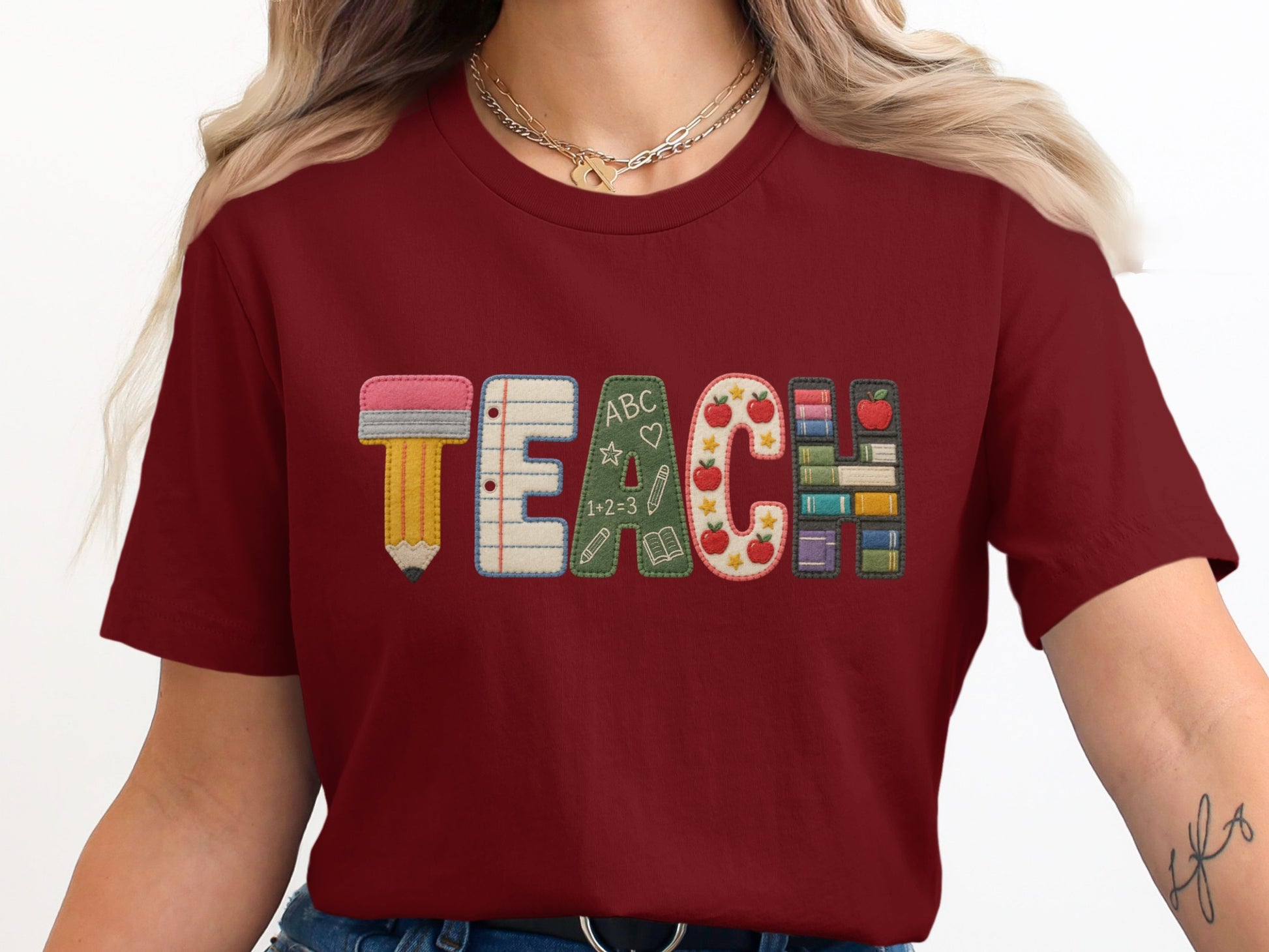 Maroon t-shirt with "TEACH" spelled out with school-themed letter designs.