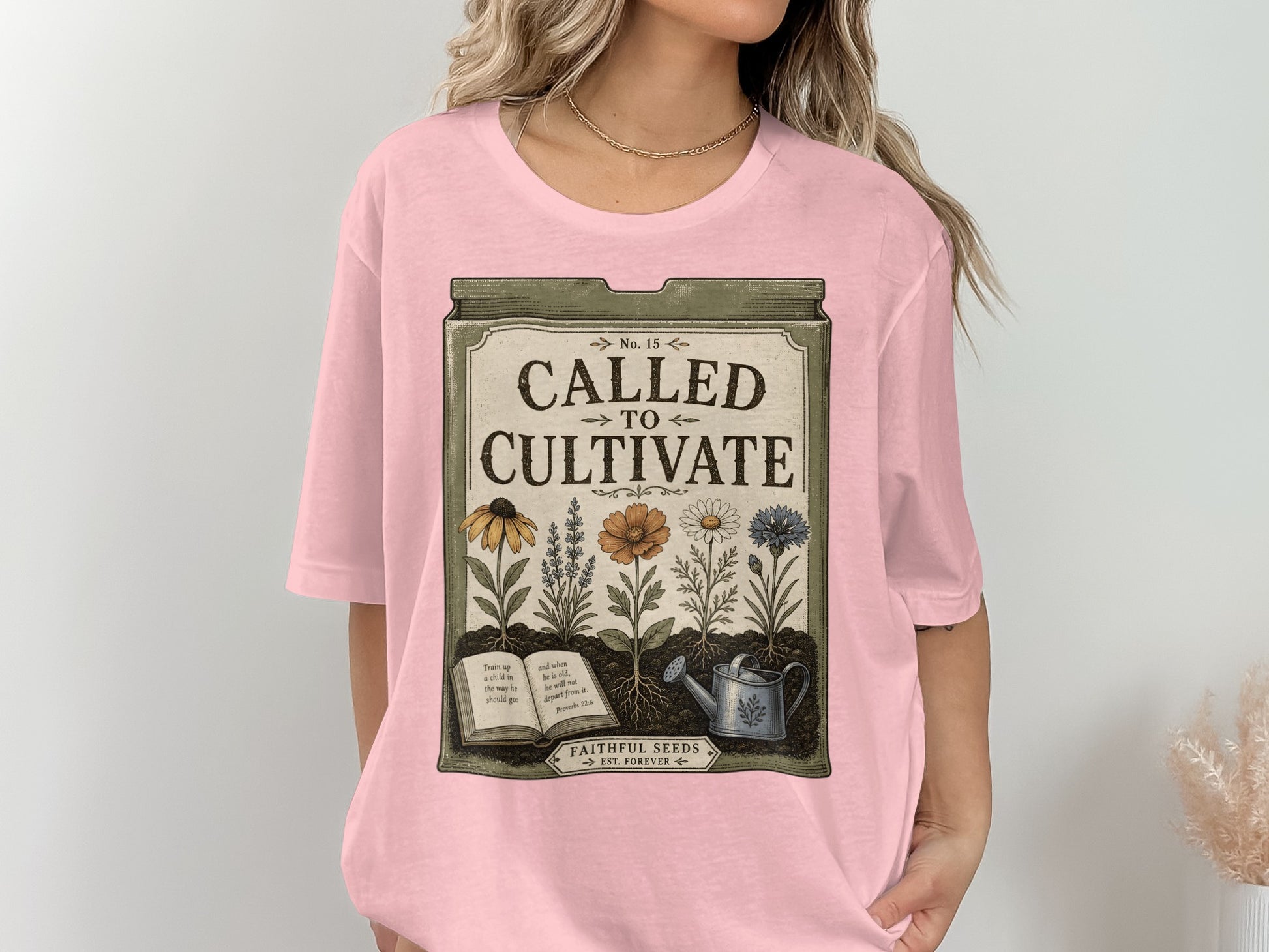 Pink t-shirt with a seed packet design featuring flowers, book, and watering can.