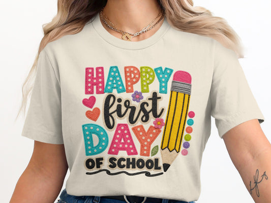 Cream t-shirt with "Happy first day of school" text and a pencil graphic.