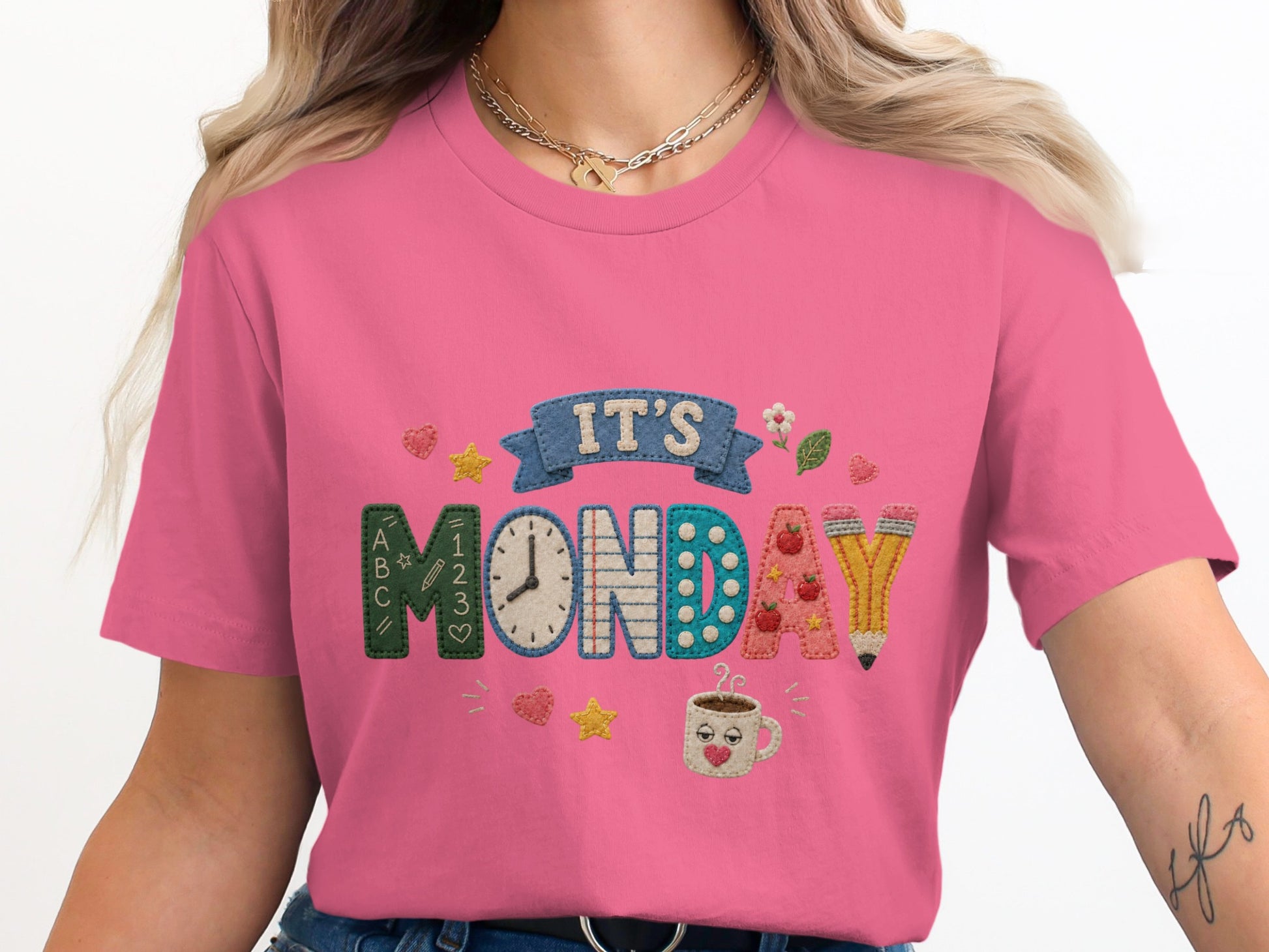 Pink t-shirt with embroidered text "IT'S MONDAY" and school-themed graphics.