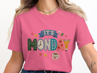 Pink t-shirt with embroidered text "IT'S MONDAY" and school-themed graphics.