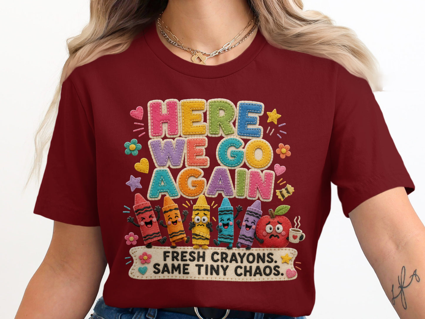 Maroon t-shirt with "HERE WE GO AGAIN" and cartoon crayons and apple design.
