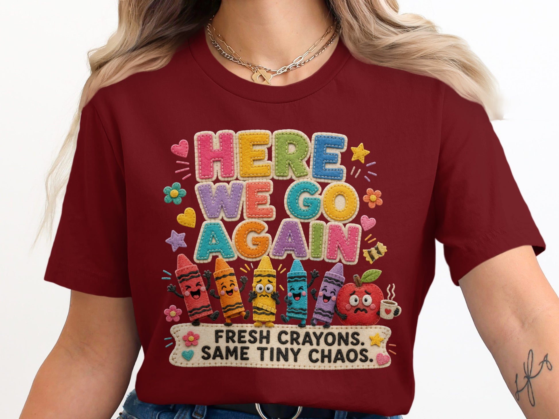 Maroon t-shirt with "HERE WE GO AGAIN" and cartoon crayons and apple design.