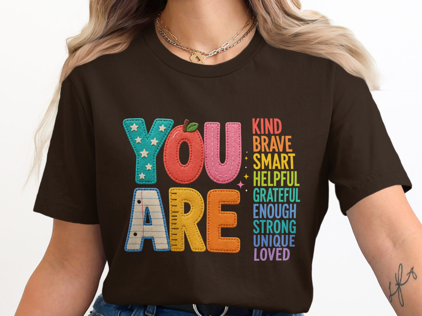 "You Are" text with uplifting words, on a brown t-shirt.