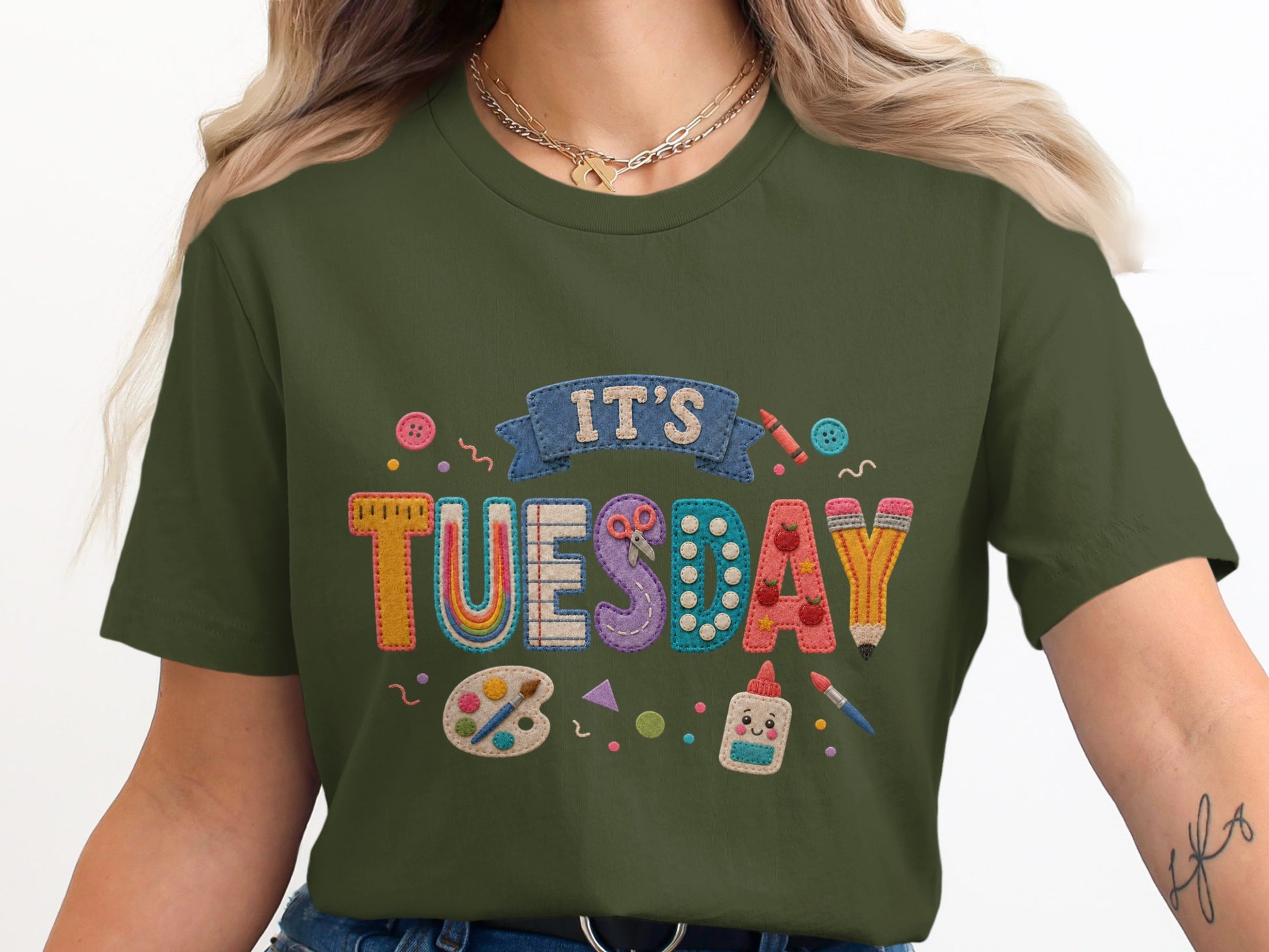 Green t-shirt with "IT'S TUESDAY" in colorful, textured letters and art supplies.