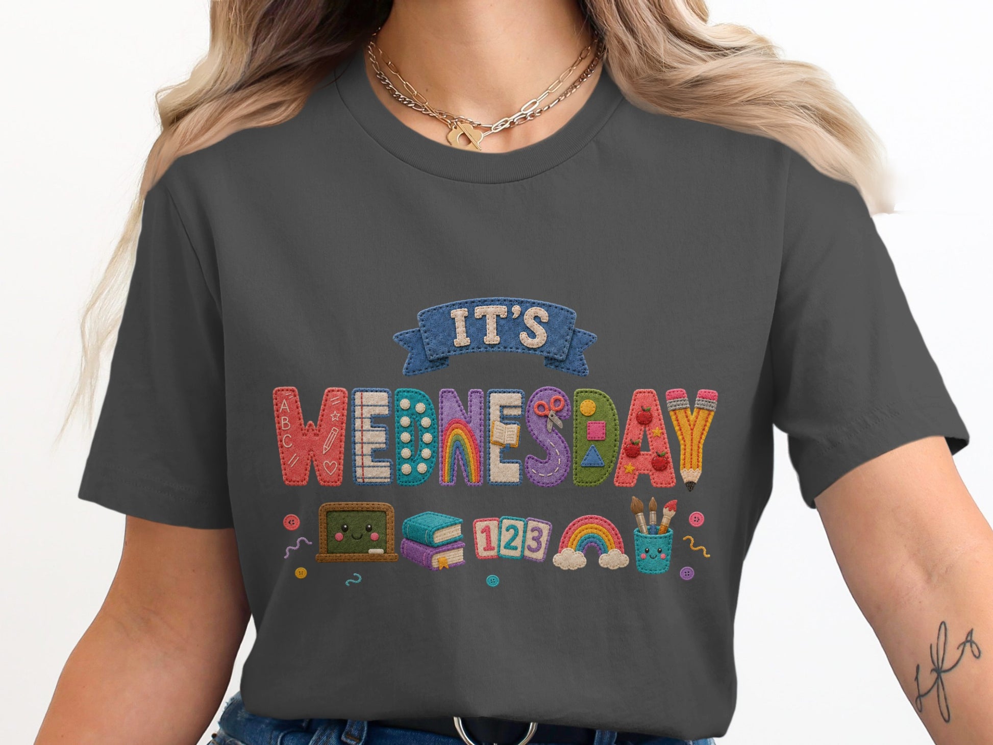 Dark grey t-shirt with "It's Wednesday" text and school-themed, embroidered-style graphics.
