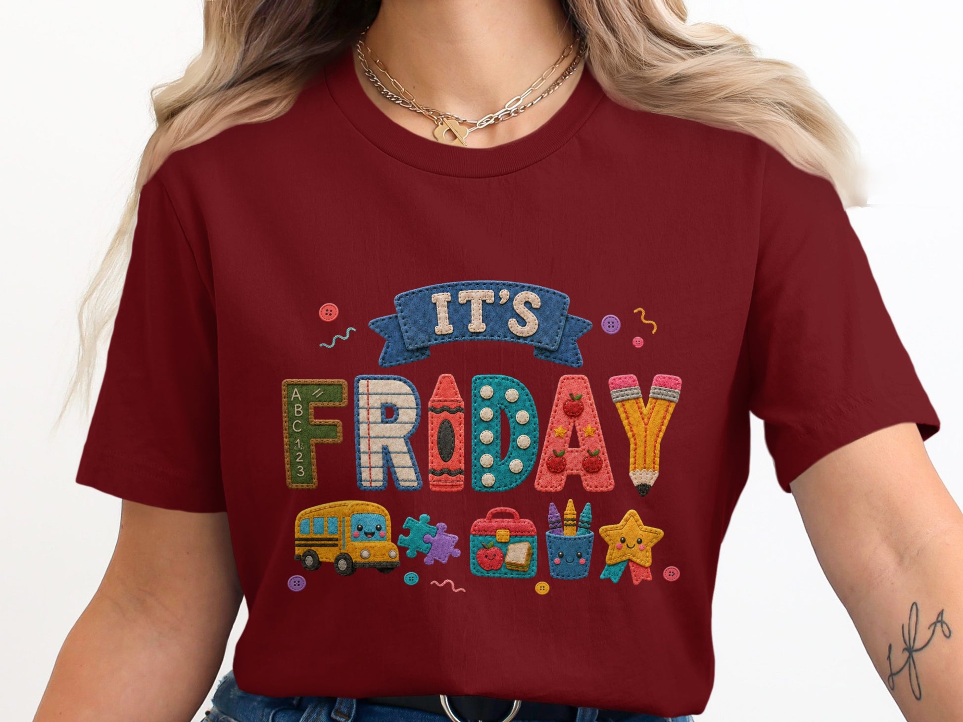 Maroon t-shirt with embroidered "IT'S FRIDAY" text and school-themed icons.
