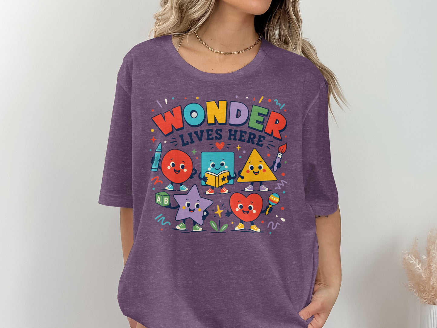 Purple t-shirt with "Wonder Lives Here" text and cute anthropomorphic shapes.