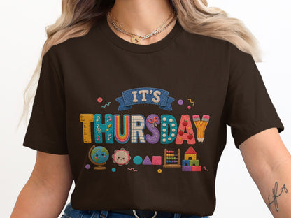 Brown t-shirt with "IT'S THURSDAY" stitched with school supplies and playful icons.