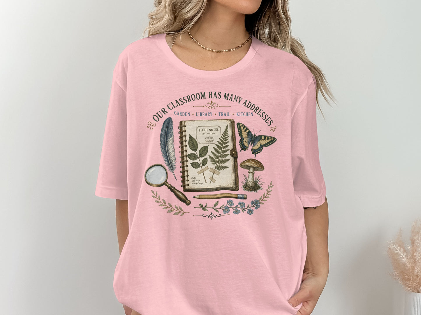 Pink t-shirt with nature-themed graphic and text "Our Classroom Has Many Addresses".