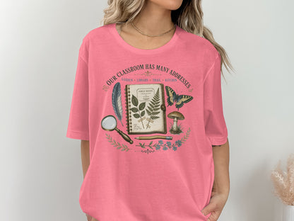 T-shirt graphic: "Our Classroom Has Many Addresses" with field journal, feather, butterfly, and mushroom.