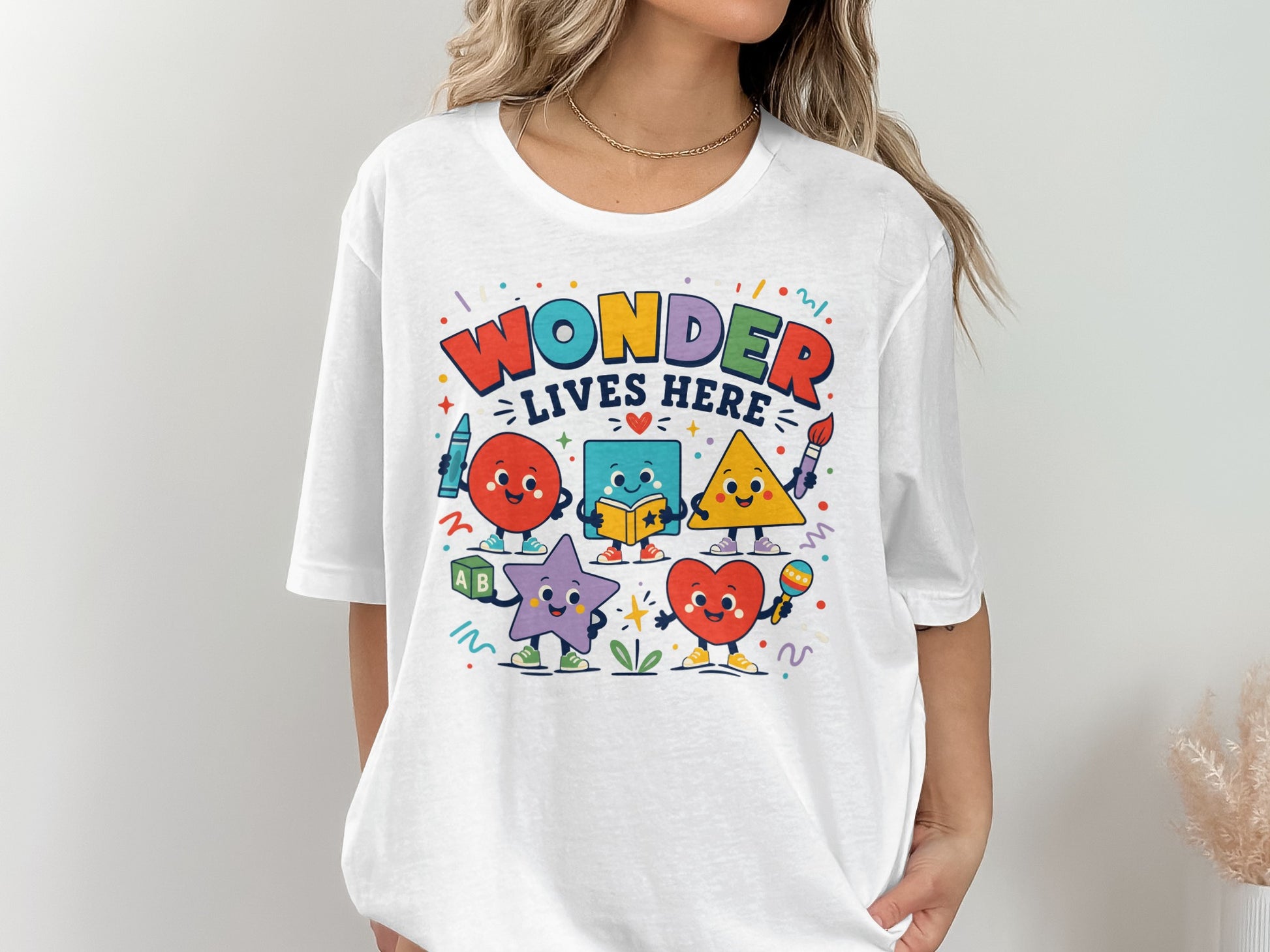 White t-shirt with colorful "Wonder Lives Here" text and cartoon shapes.
