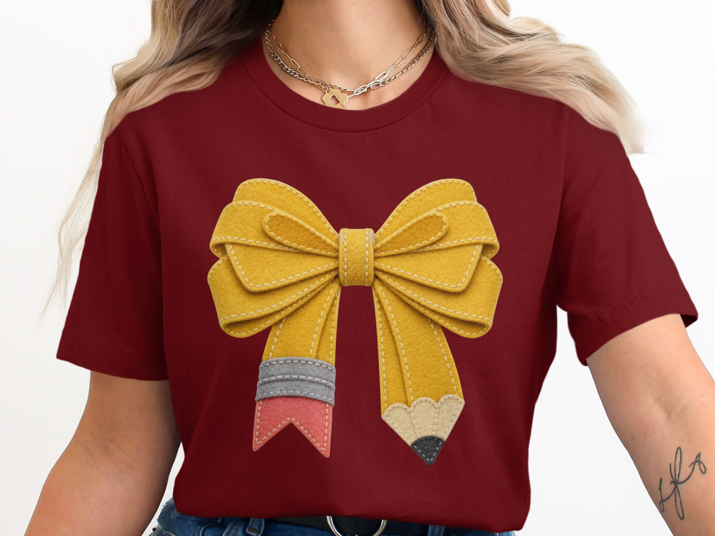 Maroon t-shirt with a yellow bow designed like a pencil with colorful accents.