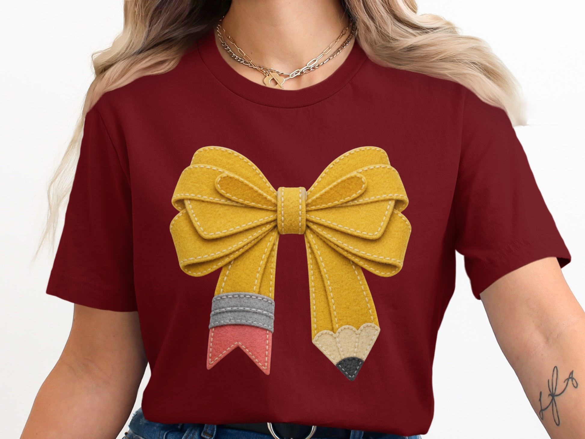 Maroon t-shirt with a yellow bow designed like a pencil with colorful accents.