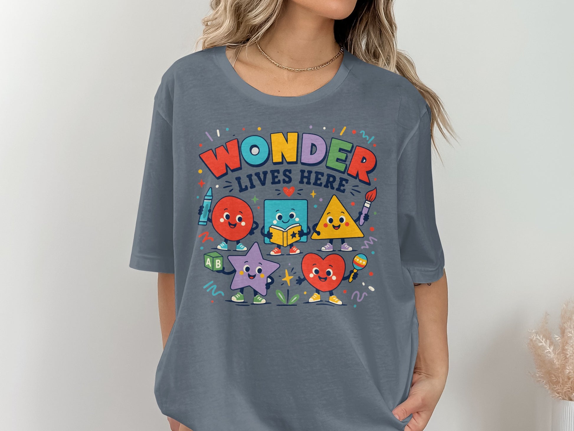Colorful cartoon shapes with text "Wonder Lives Here" on a grey t-shirt.