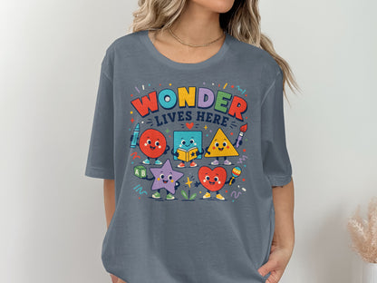 Colorful cartoon shapes with text "Wonder Lives Here" on a grey t-shirt.