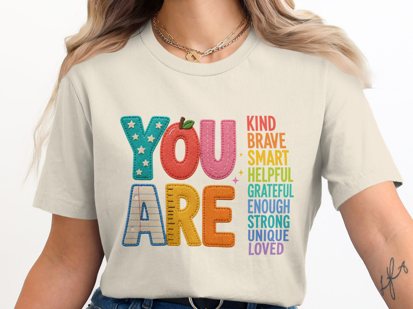 Shirt with "YOU ARE KIND BRAVE SMART HELPFUL GRATEFUL ENOUGH STRONG UNIQUE LOVED" text.
