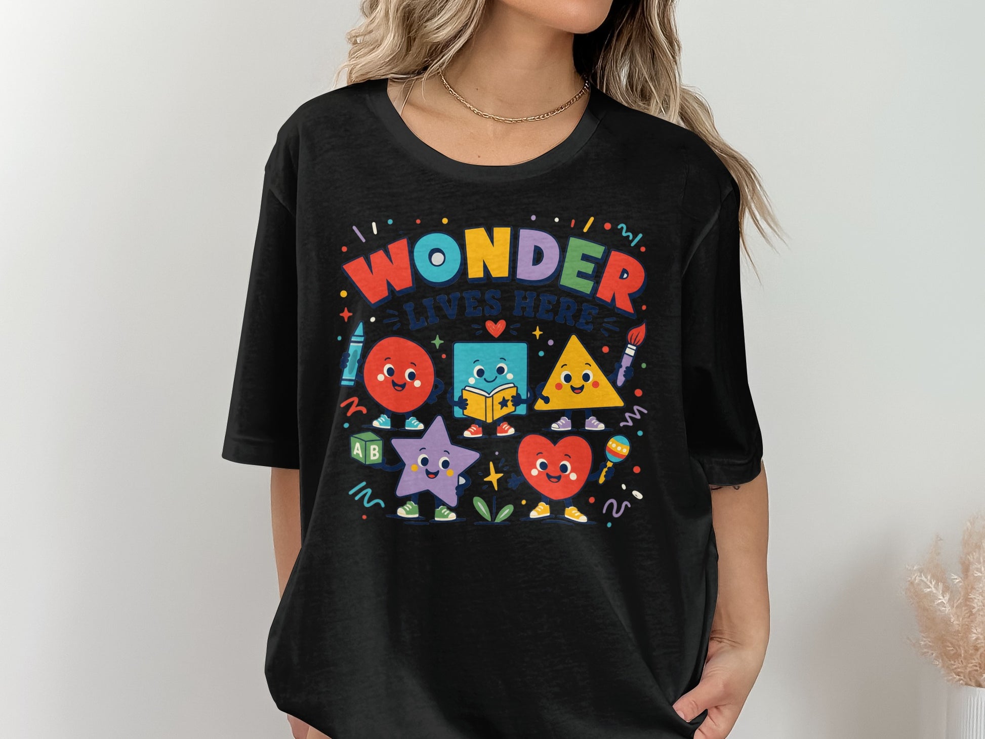 Black t-shirt with colorful cartoon shapes and text "WONDER LIVES HERE"
