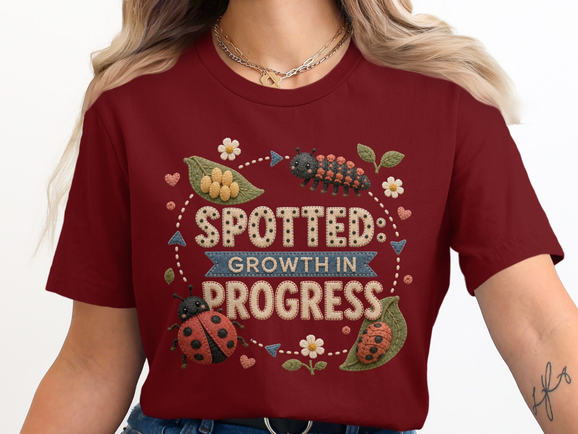 Maroon t-shirt with "Spotted: Growth in Progress" text and ladybugs.