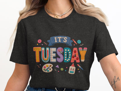 Dark t-shirt with "IT'S TUESDAY" in embroidered classroom applique letters.