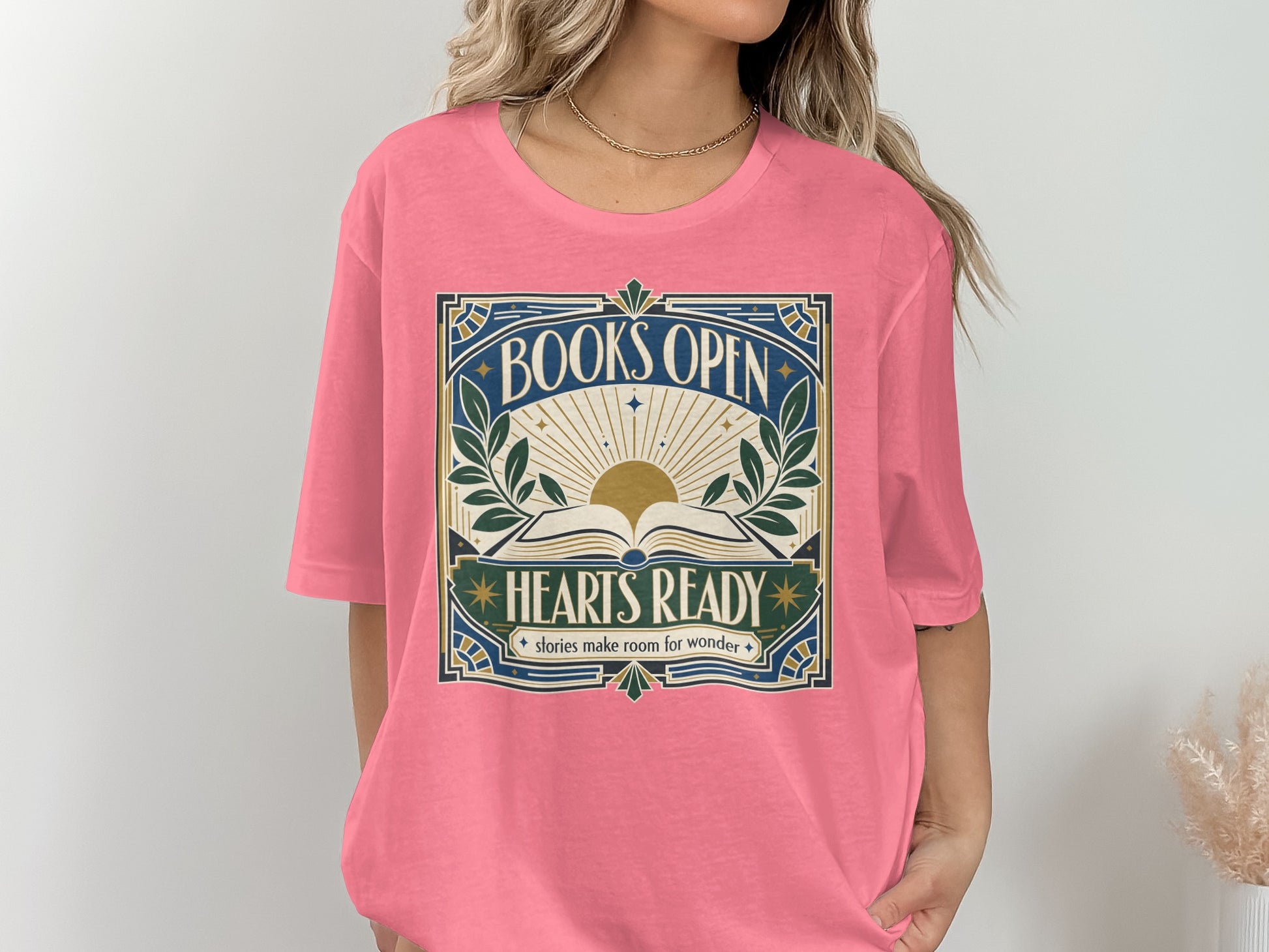 Pink t-shirt with "BOOKS OPEN HEARTS READY stories make room for wonder" text and sun design.
