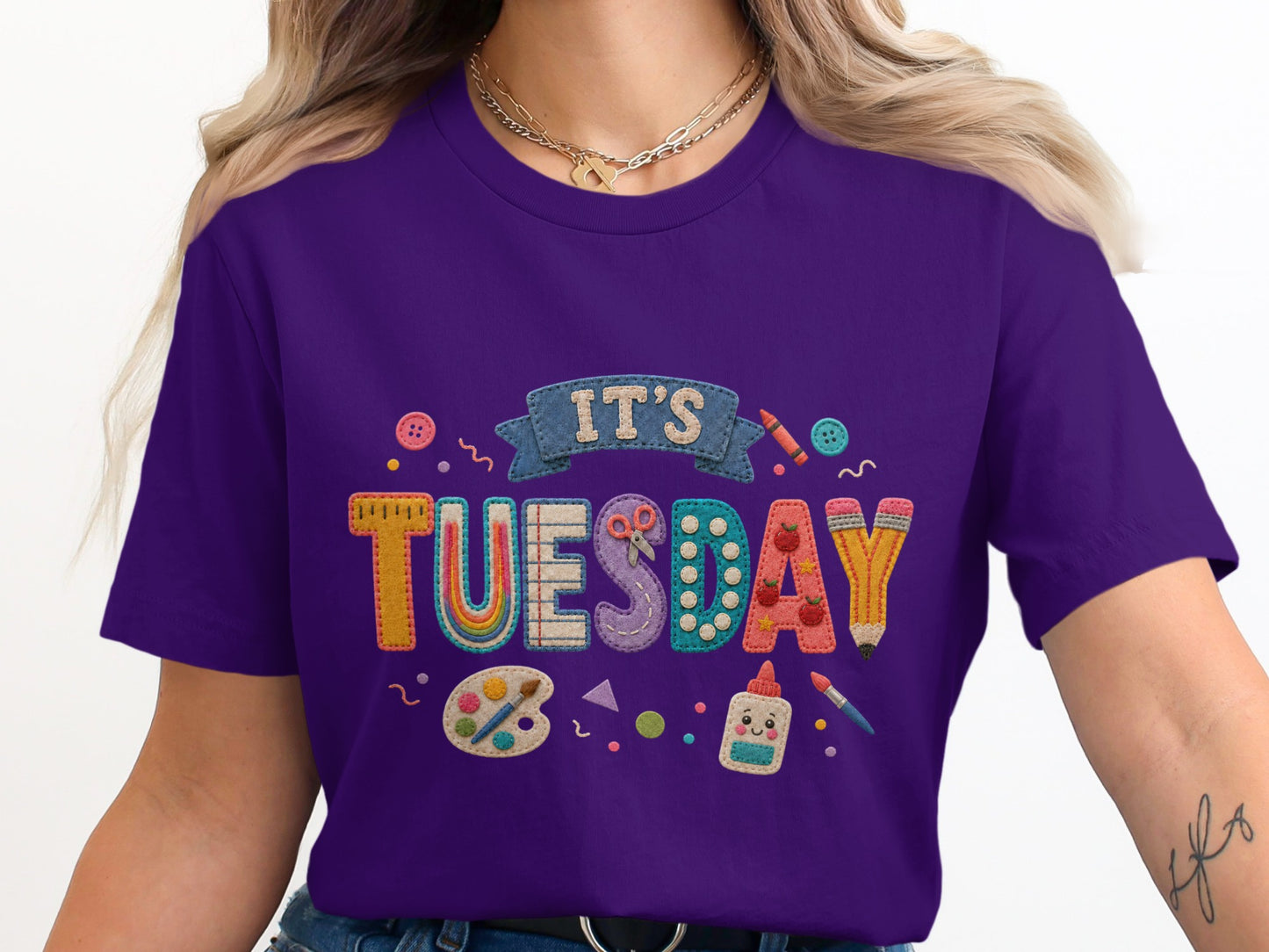 Purple t-shirt with "It's Tuesday" graphic featuring art supplies.