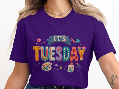 Purple t-shirt with "It's Tuesday" graphic featuring art supplies.