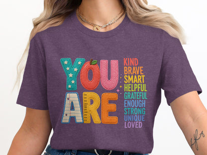 Purple t-shirt with "YOU ARE KIND BRAVE SMART HELPFUL GRATEFUL ENOUGH STRONG UNIQUE LOVED."