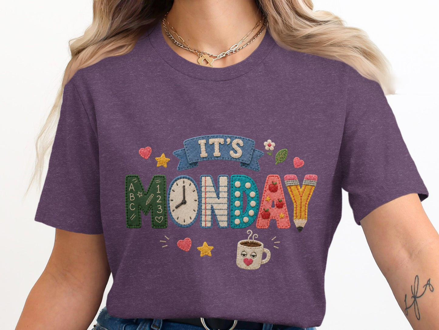 Purple t-shirt with embroidered text "IT'S MONDAY" and school-themed graphics.
