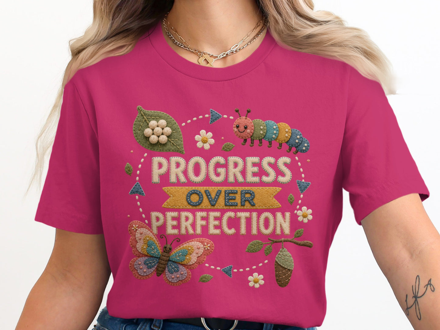Progress Over Perfection on a pink t-shirt with caterpillar, butterfly, and chrysalis graphics.