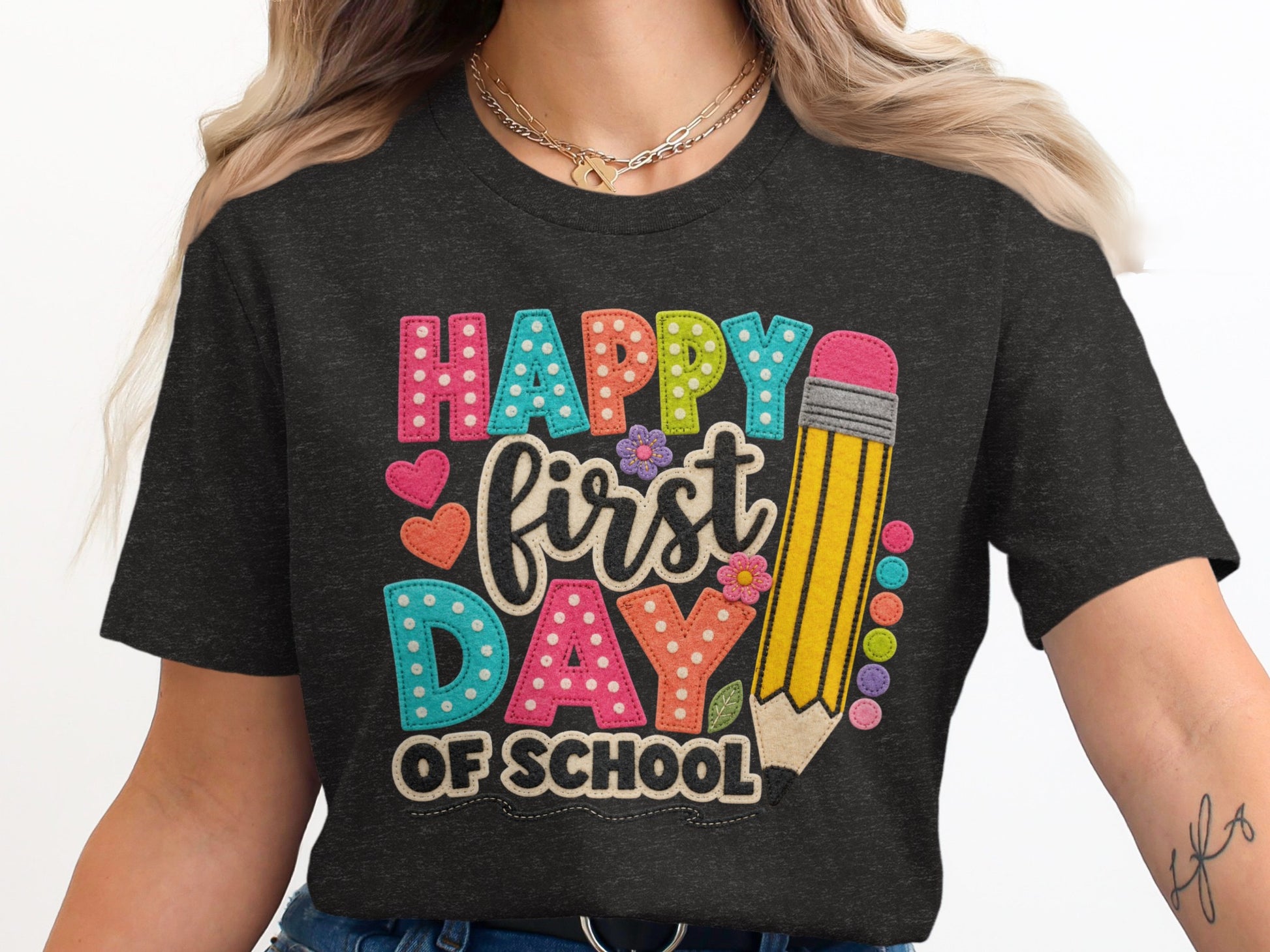 Dark t-shirt with "Happy first day of school" in colorful, textured letters and a pencil graphic.