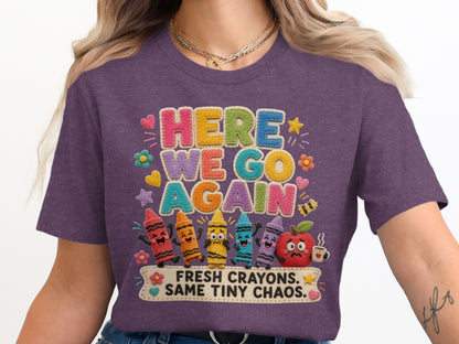 Purple t-shirt with "HERE WE GO AGAIN" and "FRESH CRAYONS. SAME TINY CHAOS." text.