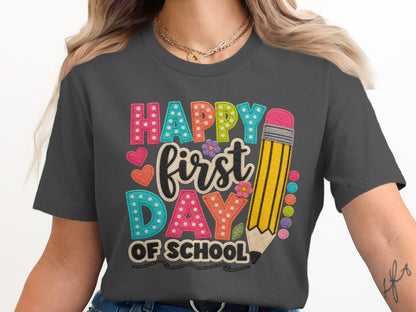 Grey t-shirt graphic with "Happy first DAY OF SCHOOL" text and a pencil.