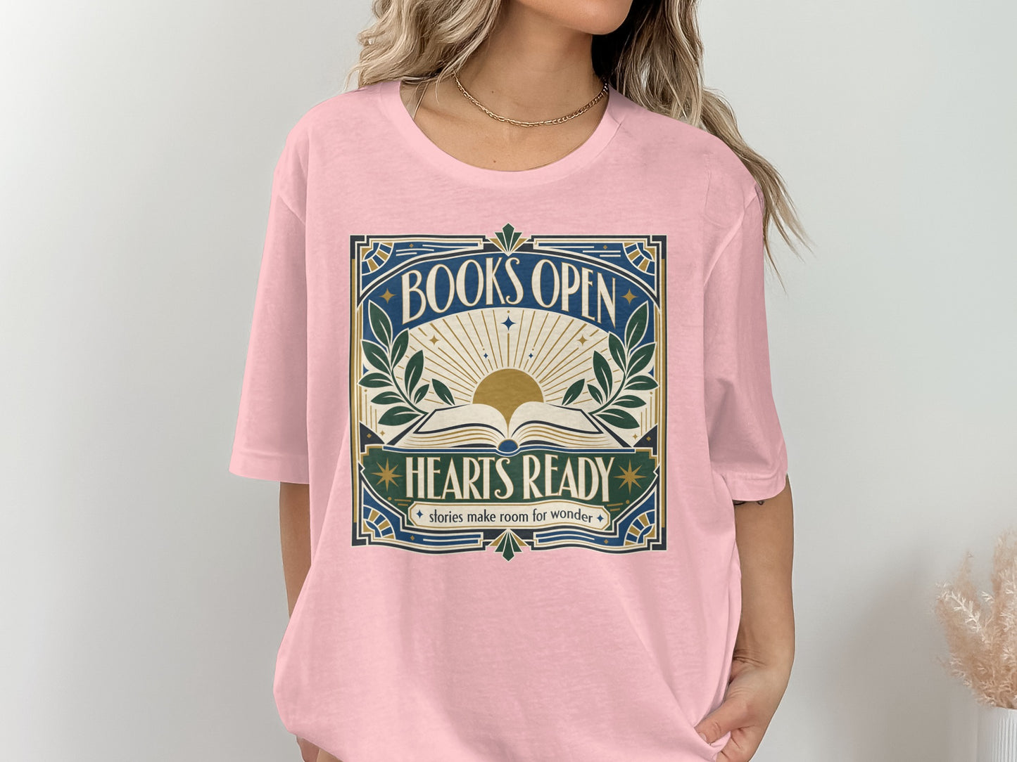 Pink t-shirt with "BOOKS OPEN HEARTS READY stories make room for wonder" graphic.