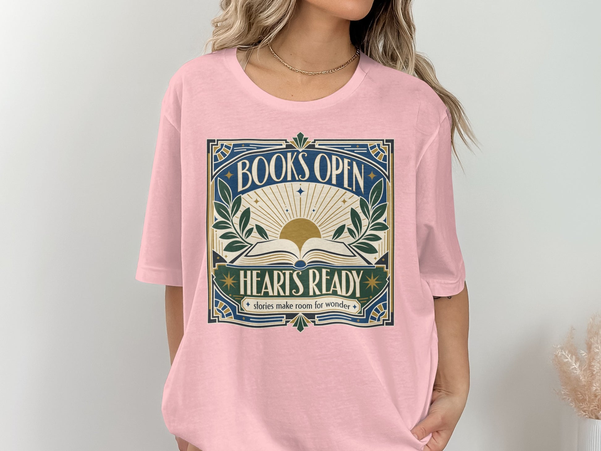 Pink t-shirt with "BOOKS OPEN HEARTS READY stories make room for wonder" graphic.