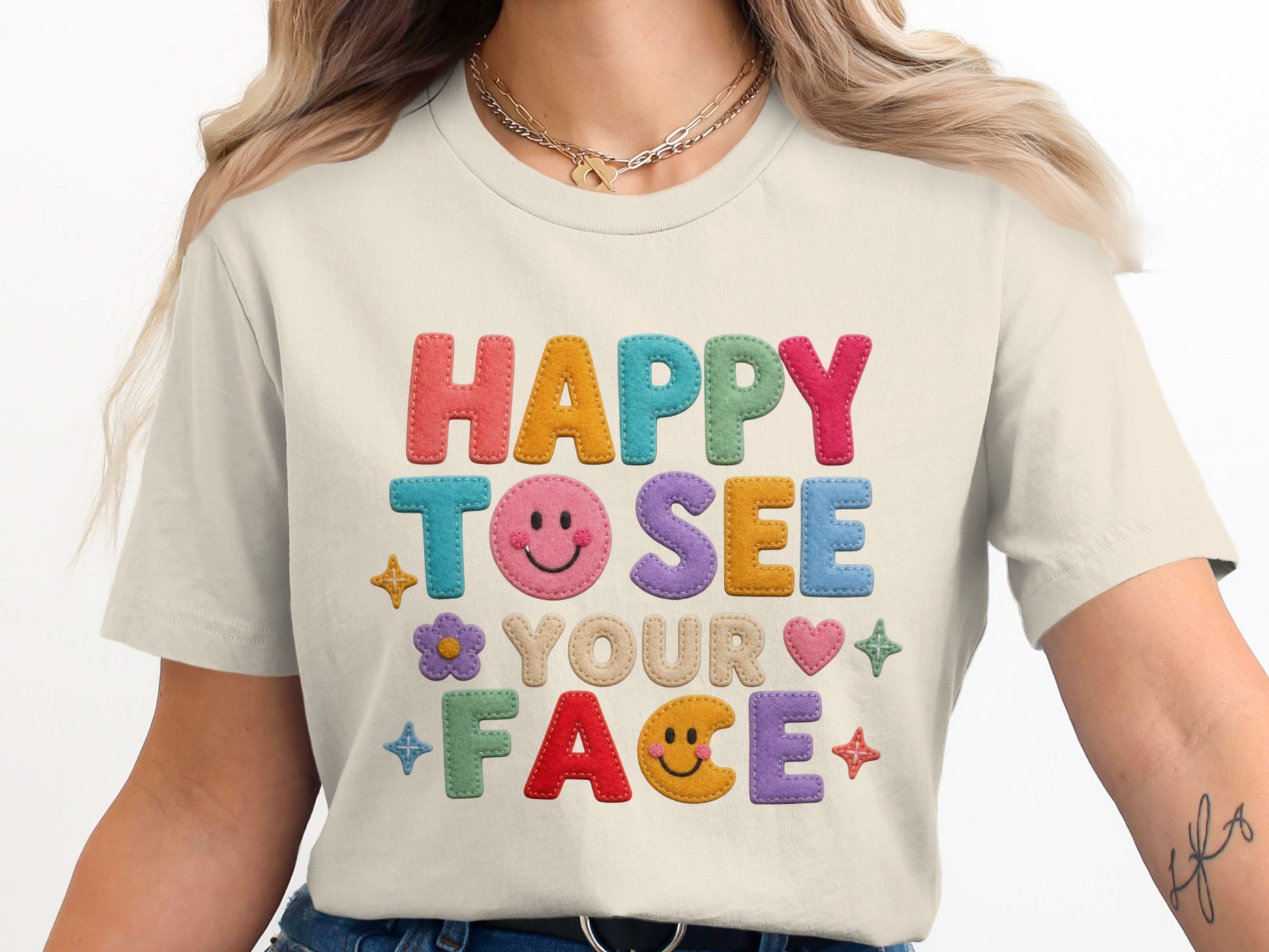T-shirt with colorful embroidered text "Happy To See Your Face" and cute embellishments.