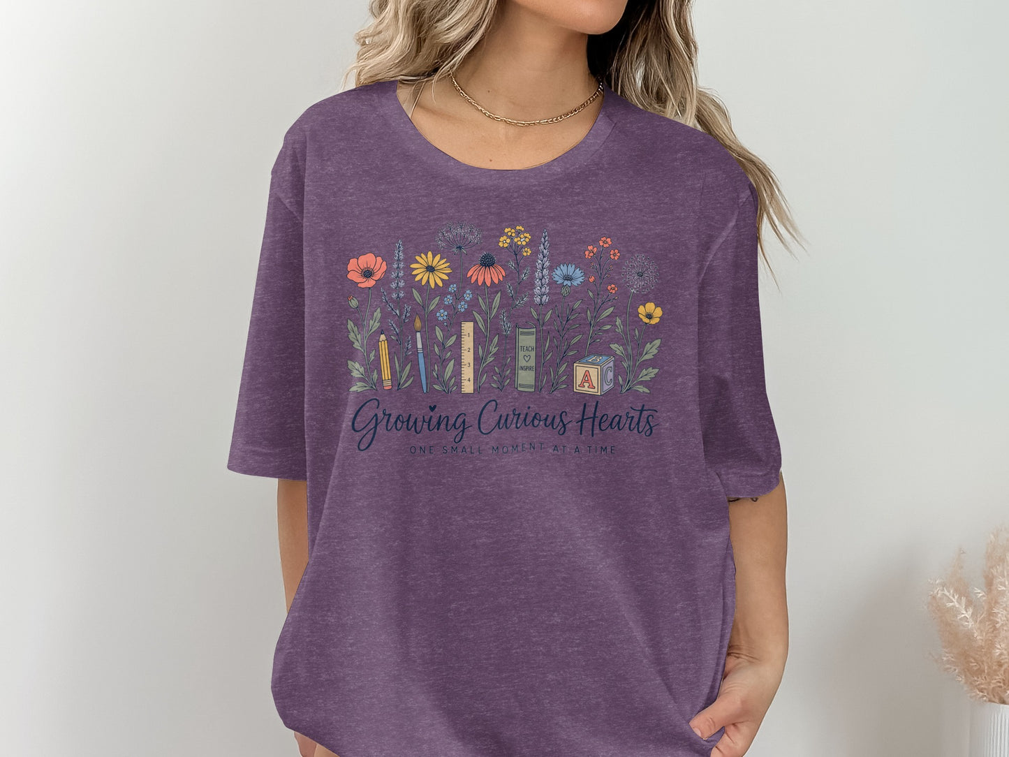 Purple t-shirt with floral design and text "Growing Curious Hearts".