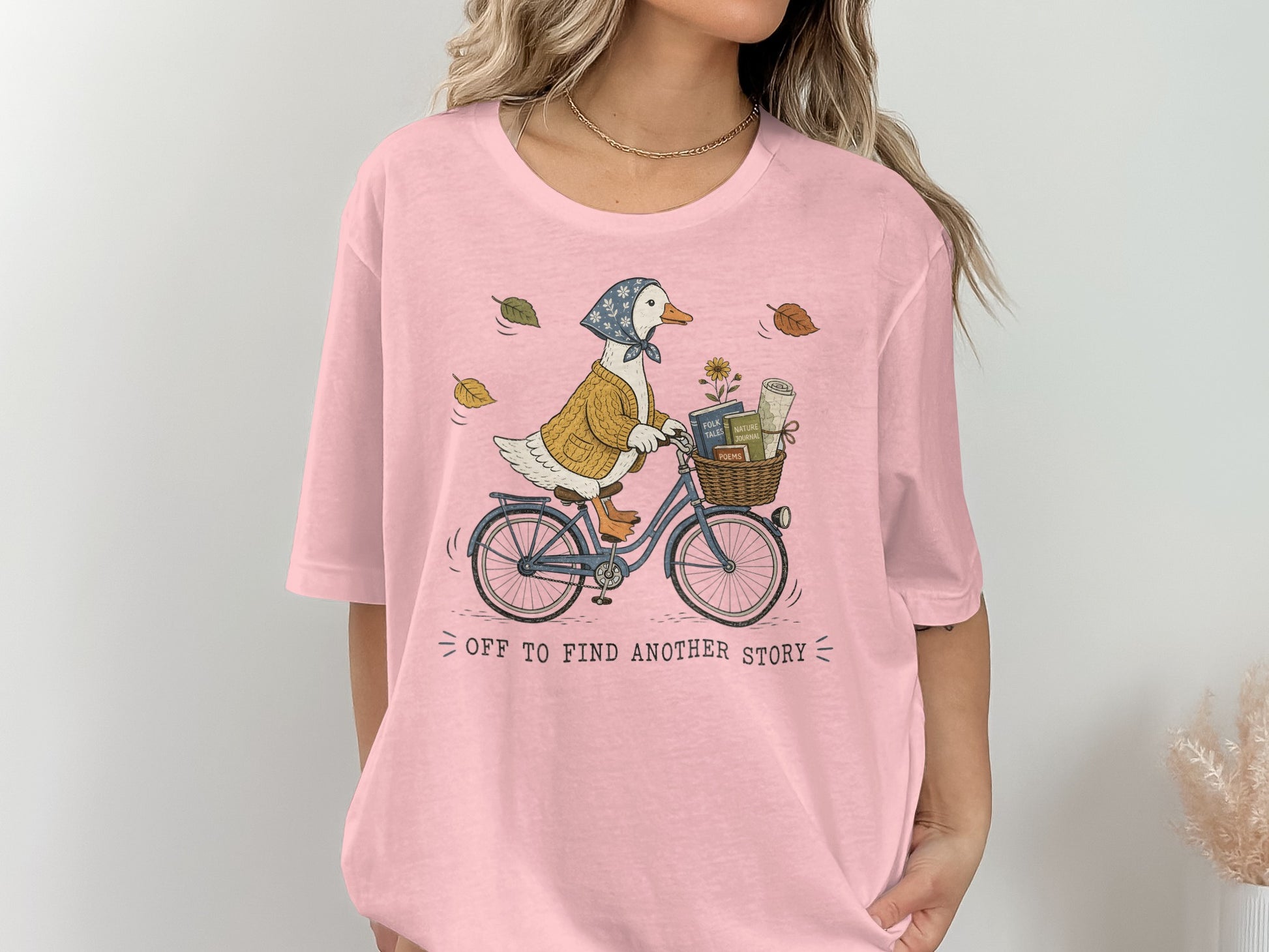 Illustration of a duck on a bicycle with books and flowers in the basket and text "off to find another story".