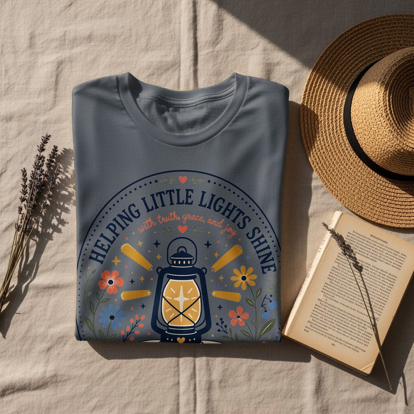 Grey t-shirt with a lantern design and text "Helping Little Lights Shine".