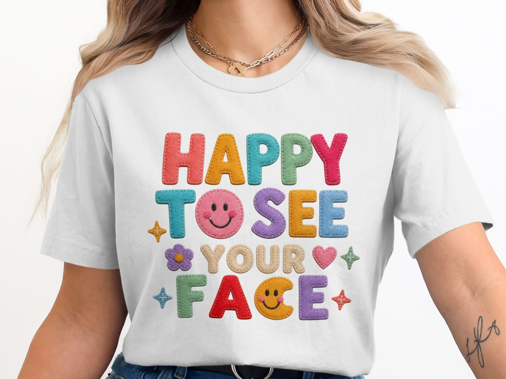 White t-shirt with colorful felt letters that read "HAPPY TO SEE YOUR FACE".