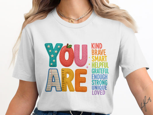 White t-shirt with "YOU ARE" and positive attributes like kind, brave, smart, loved.